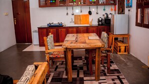 Una cocina con armarios de madera, una mesa de comedor, sillas y un refrigerador.