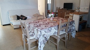 A living room with a sofa, a dining table with chairs, a TV, and a clock on the wall. - Lovely apartment 2 steps from the beach and all amenities! (SAINT CYPRIEN)
