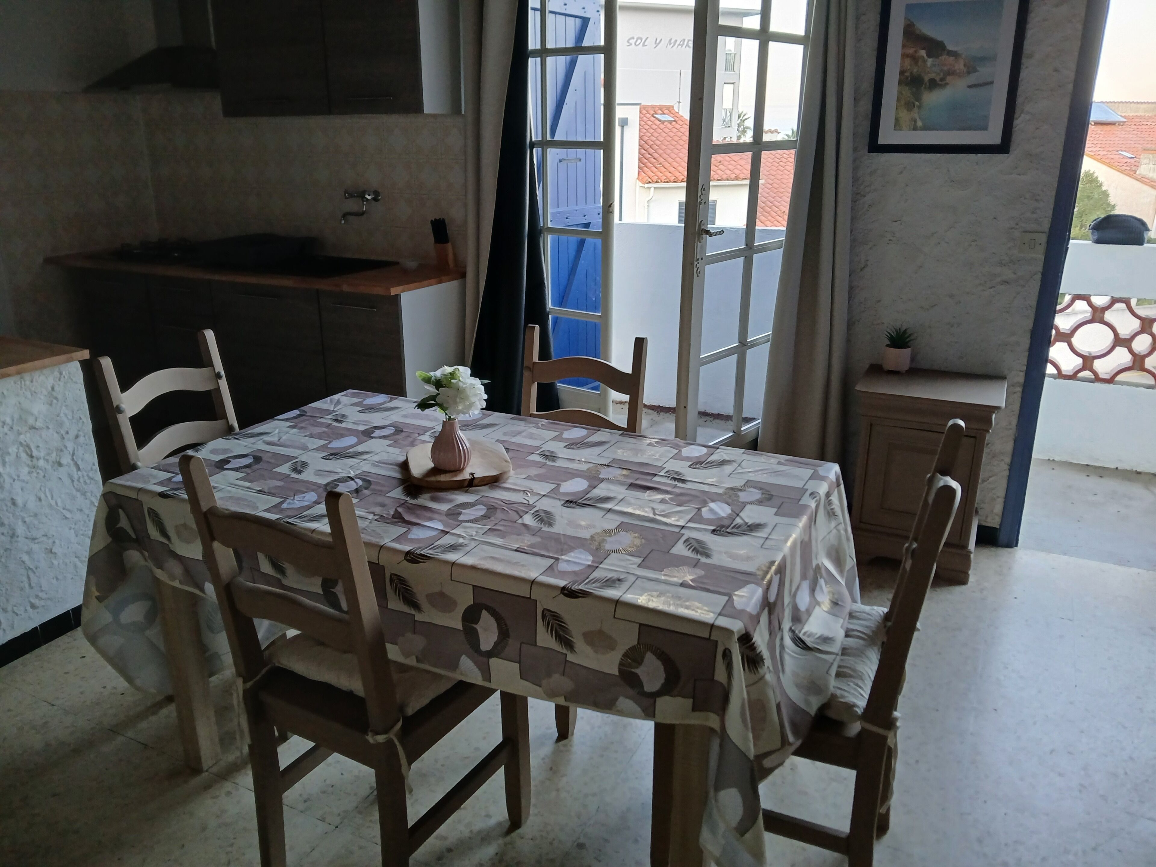 Comedor con una mesa dispuesta para cuatro personas, un florero con flores y vistas al exterior.