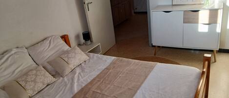 A bedroom with a bed, bedside tables, a dresser, and a wall-mounted TV.