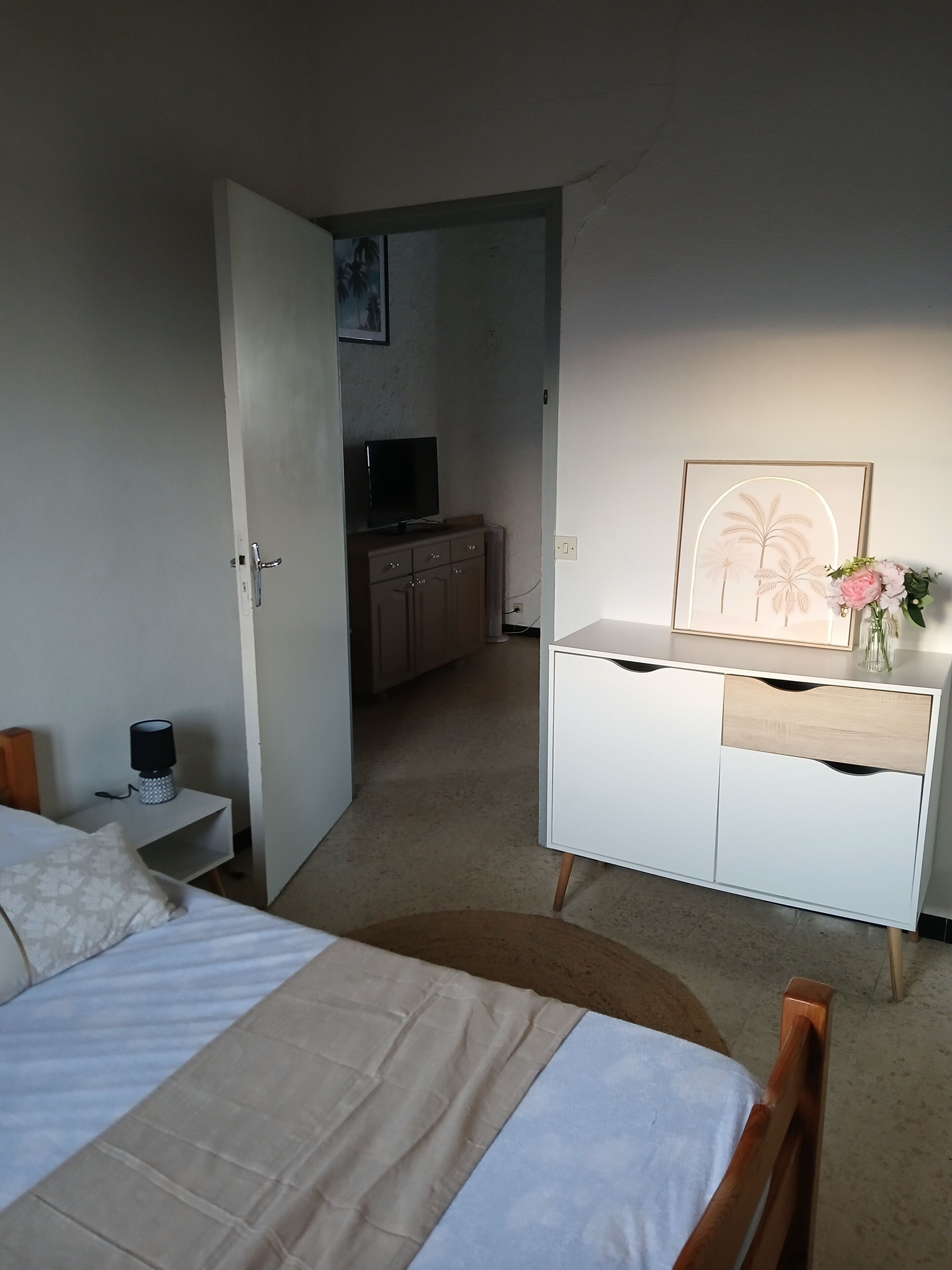 Una habitación de hotel con una cama, un aparador, un televisor y un cuadro en la pared.
