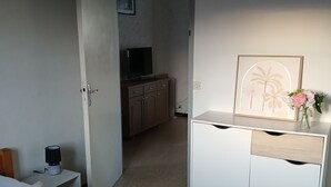 A hotel room with a bed, a dresser, a television, and a framed picture on the wall. - Lovely apartment 2 steps from the beach and all amenities! (SAINT CYPRIEN)