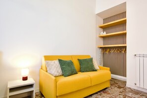 Ein gelbes Sofa mit Kissen, ein Nachttisch mit Lampe und eine Heizung.