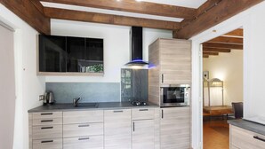 A modern kitchen with a built-in microwave, a stainless steel sink, and wooden cabinets. - Rural Cottage “La Rivière Assoiffée” with Garden and Wi-Fi (Florimont-Gaumier)