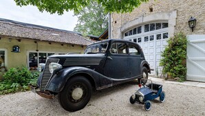 A vintage car parked in front of a stone building with a garage. - Rural Cottage “La Rivière Assoiffée” with Garden and Wi-Fi (Florimont-Gaumier)