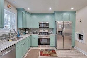 A kitchen with teal cabinets, stainless steel appliances, a microwave, oven, and refrigerator. - Sunny Crest Stay – NEW 2BR, Near Beach (Wildwood)