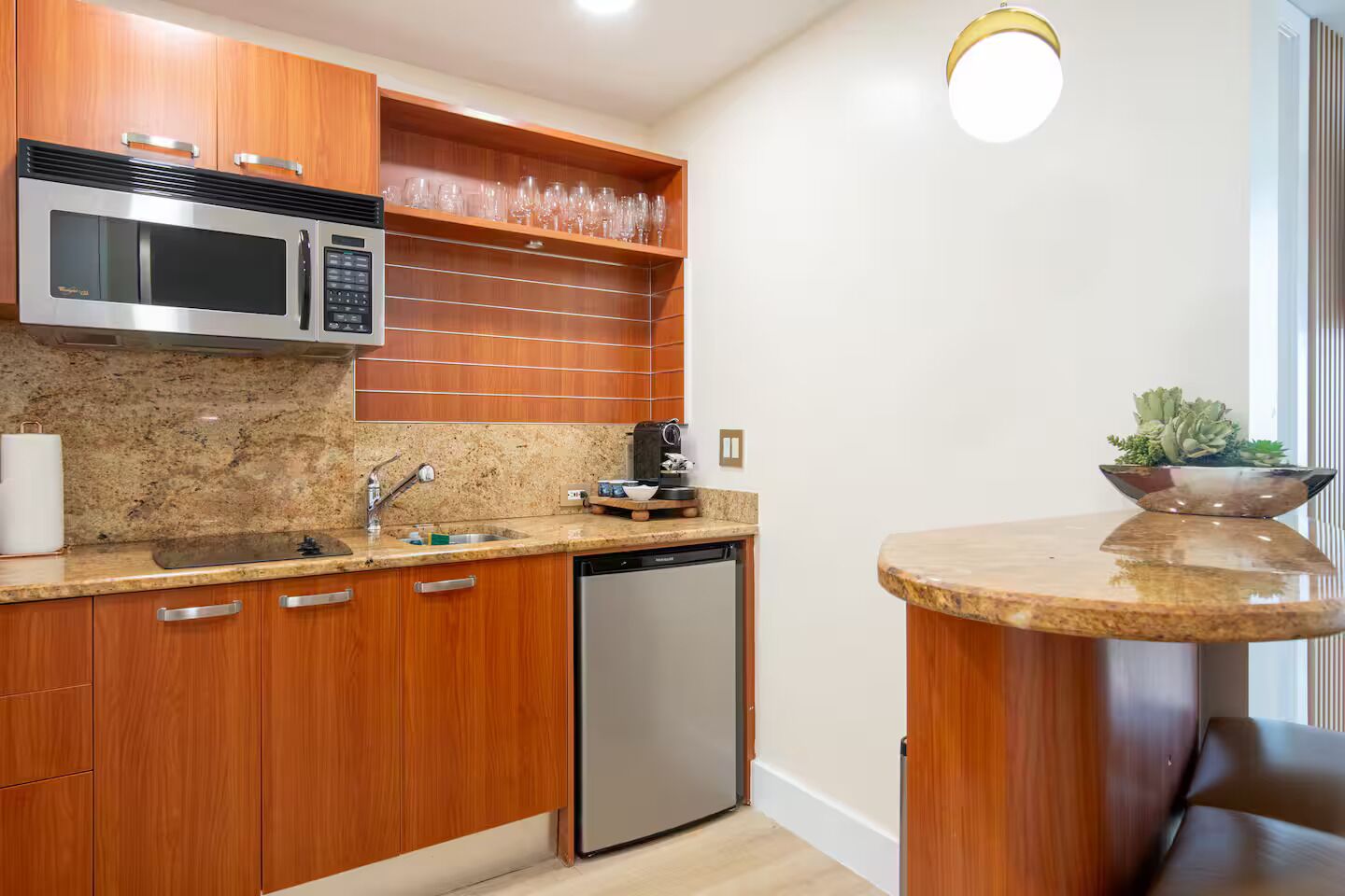 A compact kitchen with a built-in microwave, a sink, a dishwasher, wooden cabinets, and a countertop.