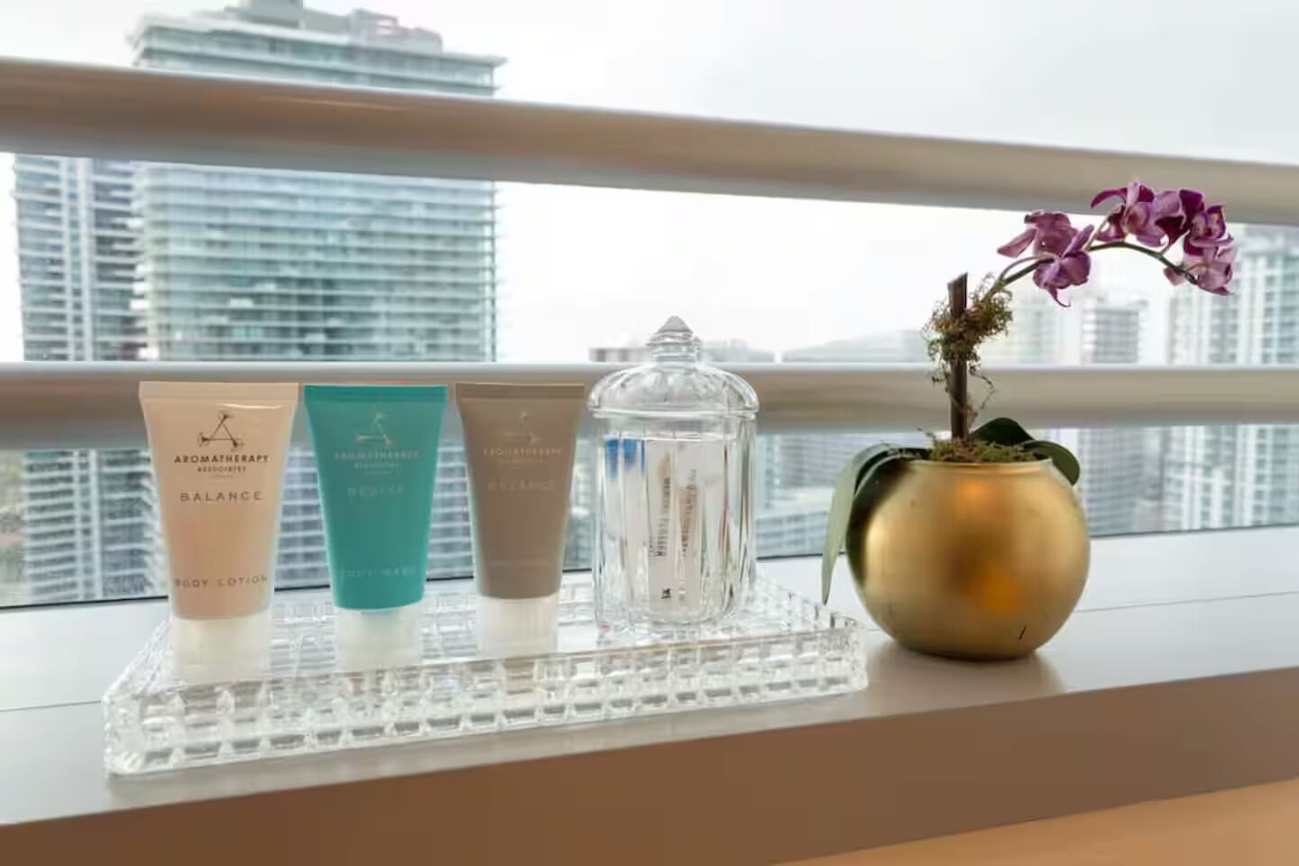 Un alféizar con productos para el cuidado de la piel y una orquídea en maceta.