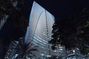 Ein modernes Hochhaus mit einer markanten, geschwungenen Glasfassade, umgeben von Bäumen.