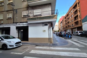 A street view with a white car parked on the side, a blue scooter, and a building with a balcony and a sign that reads '6F'. - Mediterranean-Style Apartment, 6th Floor, Wi-Fi + Air Conditioning (Valencia)