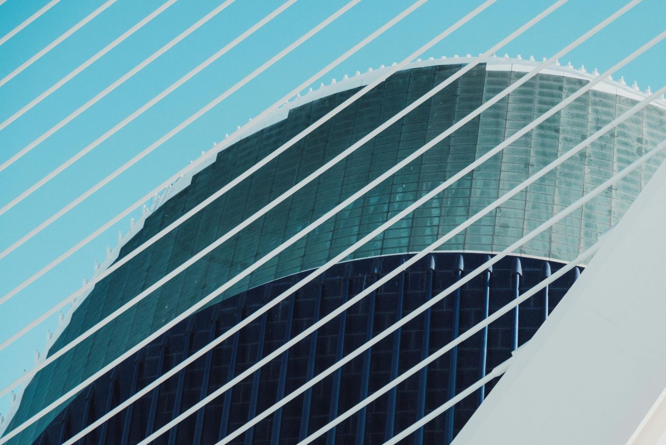 Un bâtiment moderne doté d’une façade en verre incurvée et d’une structure blanche à nervures sur sa partie supérieure.