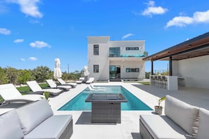 A modern two-story house with a swimming pool, outdoor seating, and a covered patio area. - Private Pool, Fire Pit & BBQ Near Grace Bay (Long Bay Hills)