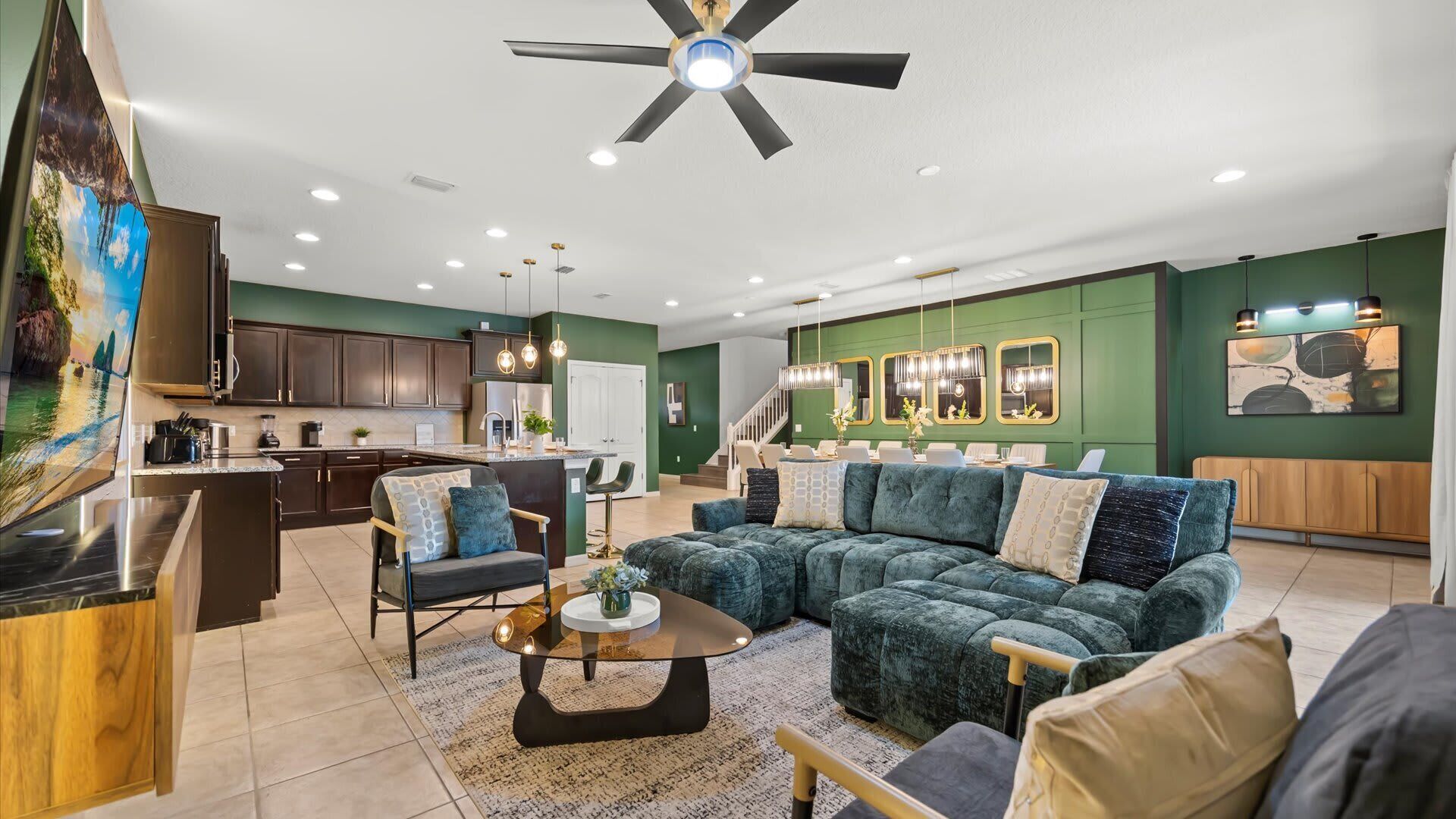 A modern living room with a sectional sofa, a coffee table, and a dining area with a kitchen in the background.