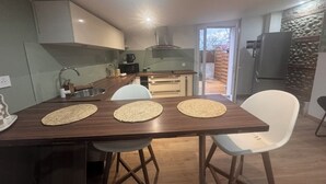 Ett modernt kök med en central köksö, vita stolar och ett matbord med bordsplaceringar.
