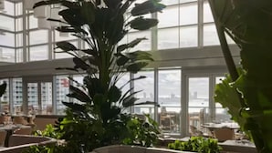 Un ristorante moderno con soffitti alti, ampie finestre e piante da interno.