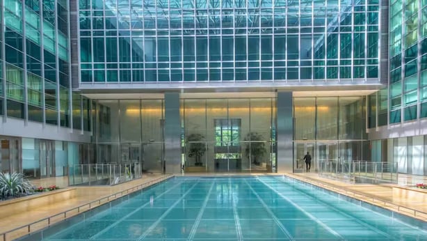 Un edificio moderno con una grande piscina interna, pareti di vetro e un ingresso centrale.