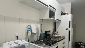 Eine kompakte Küche mit Gasherd, Mikrowelle, Waschmaschine und Kühlschrank.