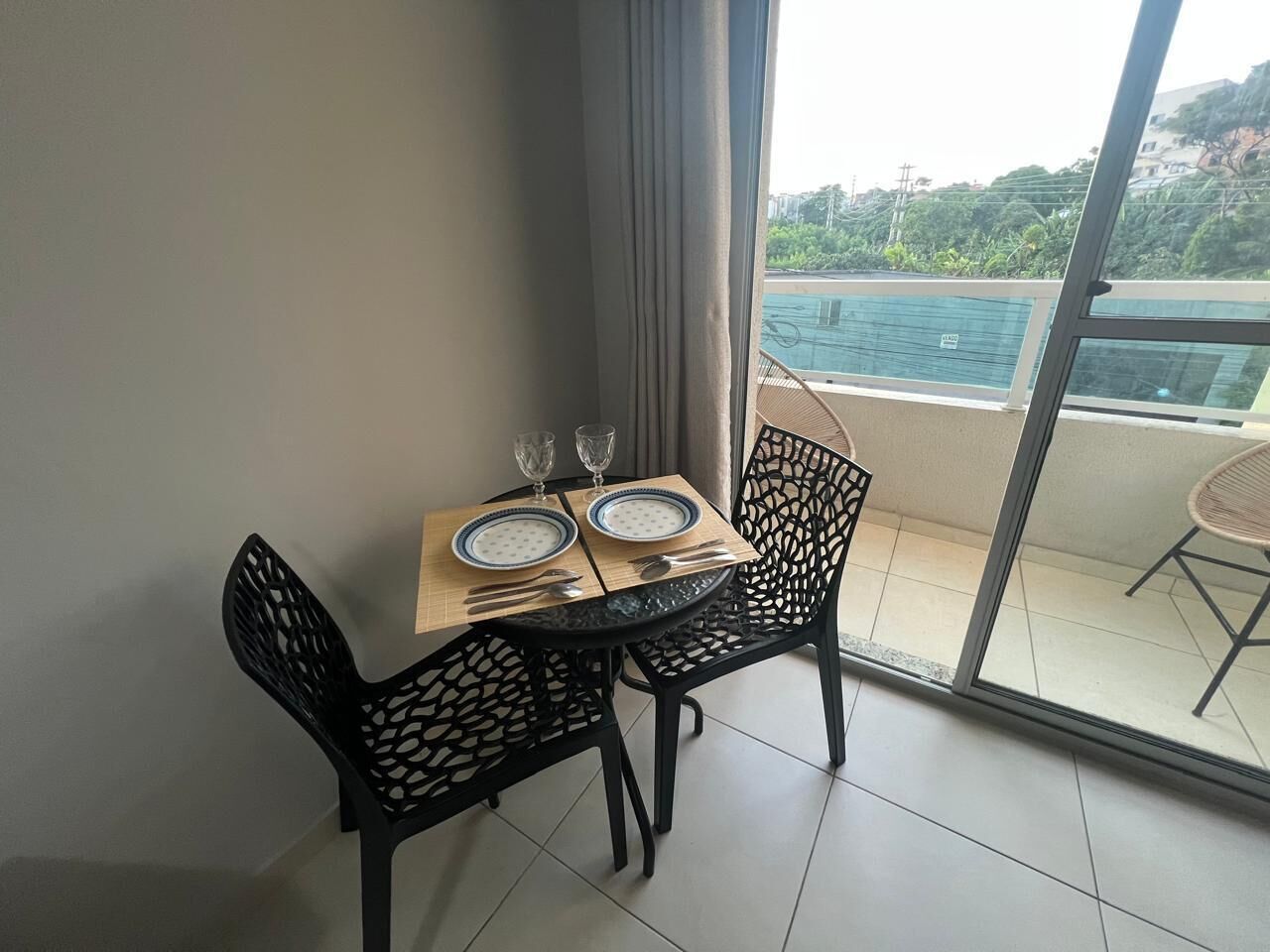 A dining area with a table set for two, black chairs, and a view of a swimming pool.