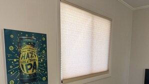 Un comedor con una mesa, dos sillas, una ventana con persianas y un cartel colgado en la pared.