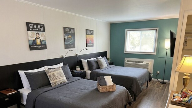 Habitación de hotel con dos camas, ventana, lámpara y decoración en la pared.