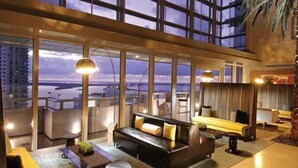 Ett modernt hotellrum med ett stort fönster, en soffa, ett soffbord och utsikt över stadsbilden.