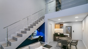 A modern interior with a staircase, a dining area, and a kitchen.