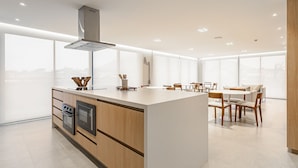 A modern kitchen with a central island, built-in oven, and stainless steel range hood.