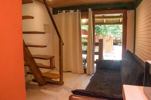 Um quarto com escada, sofá e vista para área externa.