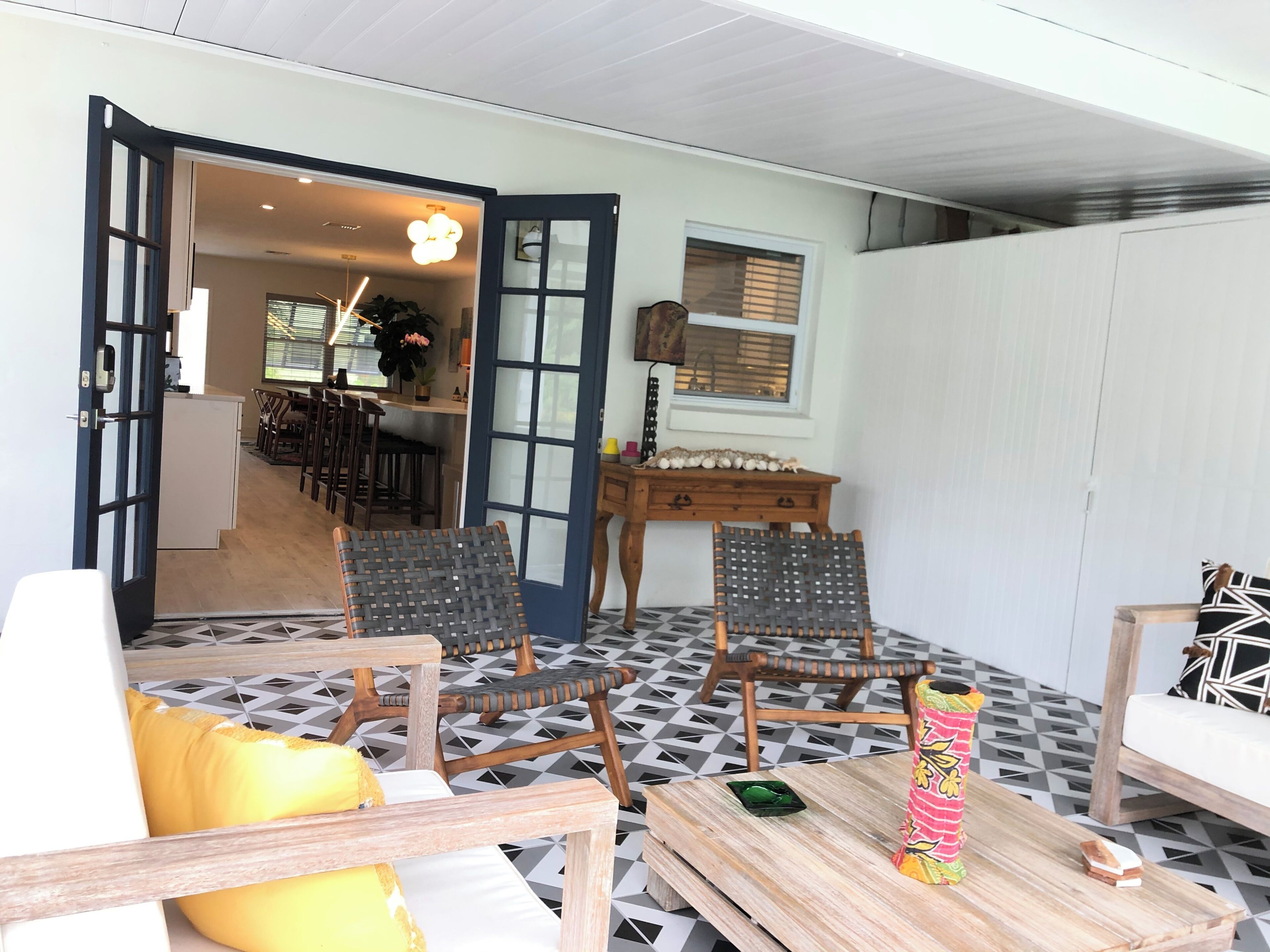 Ein Zimmer mit Essbereich, zwei Korbstühle, einem Holztisch und einem gemusterten Boden.