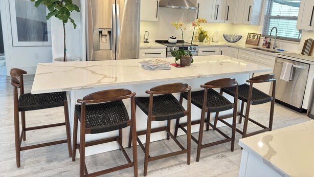 A modern kitchen with white cabinets, stainless steel appliances, and a central island with bar stools.
