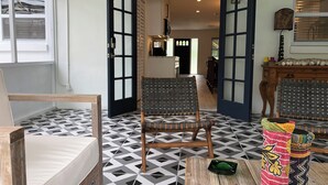 A room with a geometric patterned floor, a wooden chair, a small table, and a doorway leading to another room.