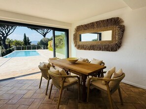 Ein Essbereich mit Blick auf einen Pool, Korbstühle und ein großes Spiegelbild.