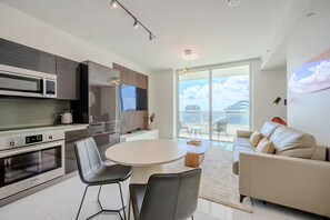Eine moderne Küche mit Essbereich, einer Couch und einem Balkon mit Blick auf die Stadt.