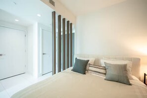 Ein modernes Schlafzimmer mit einem großen Bett, einer Tür und einer Wand mit vertikalen Holzleisten.