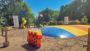 A sandy play area with a slide and a climbing structure. - Baraboo RV Resort (Baraboo)