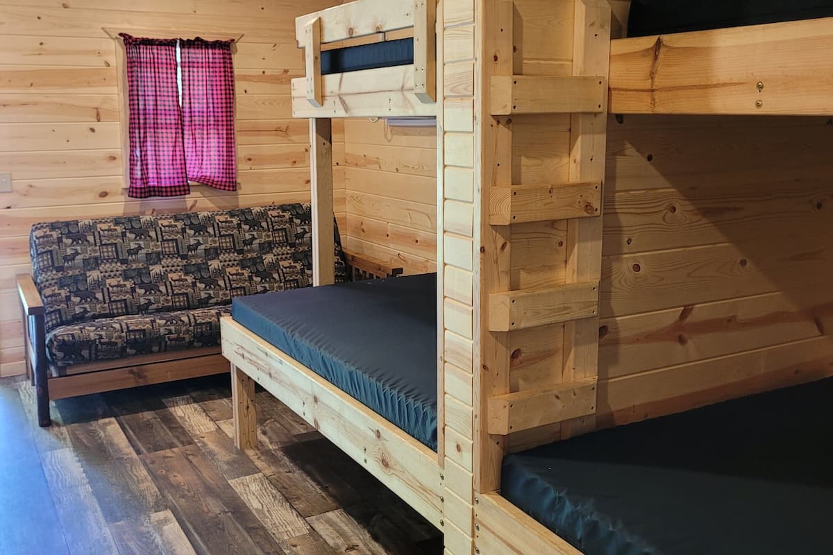 Une chambre avec un lit superposé, un canapé à motifs et une fenêtre avec des rideaux.