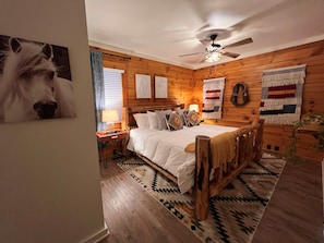 A cozy wooden room with a bed, a ceiling fan, and a rug. - Natural State Cabins - 5 Cabin Listing (Hot Springs)