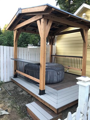 Une terrasse en bois avec un banc et un jacuzzi.