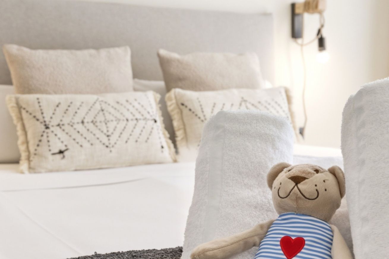 Una cama con cabecera blanca y varios almohadones, incluyendo uno decorativo.