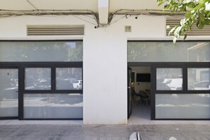 A building with large glass doors and windows, a tiled ground floor, and visible electrical wiring above. - Travel Habitat Jardin Ayora 2 WIFI+AACC (Valencia)