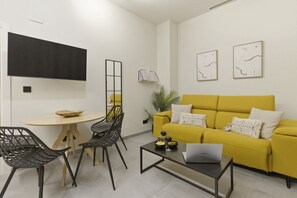 A modern living room with a yellow sofa, black chairs, a coffee table with a laptop, and artwork on the walls. - Travel Habitat Jardin Ayora 2 WIFI+AACC (Valencia)