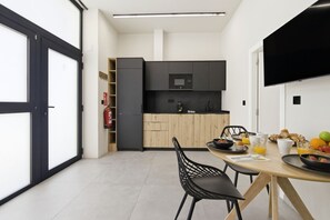 A modern kitchen with a dining area, featuring a flat-screen TV, a microwave, and a breakfast setting. - Travel Habitat Jardin Ayora 2 WIFI+AACC (Valencia)