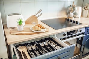 A kitchen with a toaster, a cutting board, a plant, a plate of food, and a drawer with utensils. - Elegant City Retreat | Free Parking | 13 PPL (Sheffield)