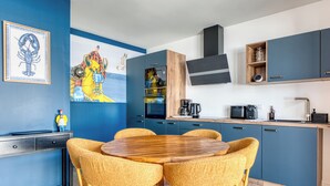 Een moderne keuken met een eethoek, met een ronde houten tafel en vier stoelen, een koffiezetapparaat en een magnetron.