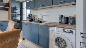 A compact kitchen with a built-in washer, a coffee maker, and a sink. - Bains de Mer House & Jacuzzi steps from the beach, Walk to town, Sleeps 6 (Saint-Gilles-Croix-de-Vie)