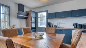 A modern kitchen with a dining table, chairs, and a coffee maker. - Bains de Mer House & Jacuzzi steps from the beach, Walk to town, Sleeps 6 (Saint-Gilles-Croix-de-Vie)
