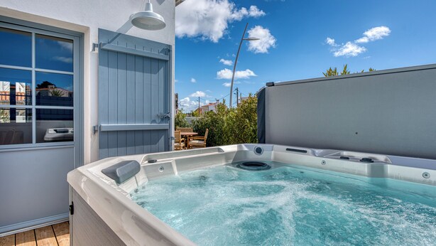 A hot tub on a wooden deck with a view of the sky and buildings. - Bains de Mer House & Jacuzzi steps from the beach, Walk to town, Sleeps 6 (Saint-Gilles-Croix-de-Vie)