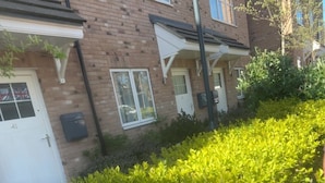 A row of brick buildings with white doors and windows, a hedge in the foreground, and a clear blue sky. - Stylish 2-Bed Apt 
| 10 Mins to Oxford Universities/city | Free private parking (Oxford)