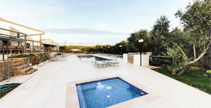 Ett poolområde med en liten pool, solstolar och en byggnad med modern design.