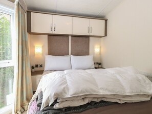 A bedroom with a bed, two bedside tables, a headboard, and a window with curtains. - The Norfolk Nook 18 Castle Walk (Great Yarmouth)